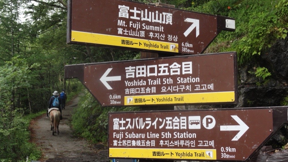 富士山五合目の登山道を歩き出す登山者。薄手の服装で歩いている