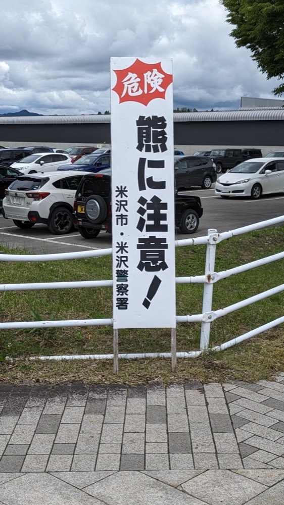 駐車場のそばに立つ「熊に注意」の看板(山形県米沢市)