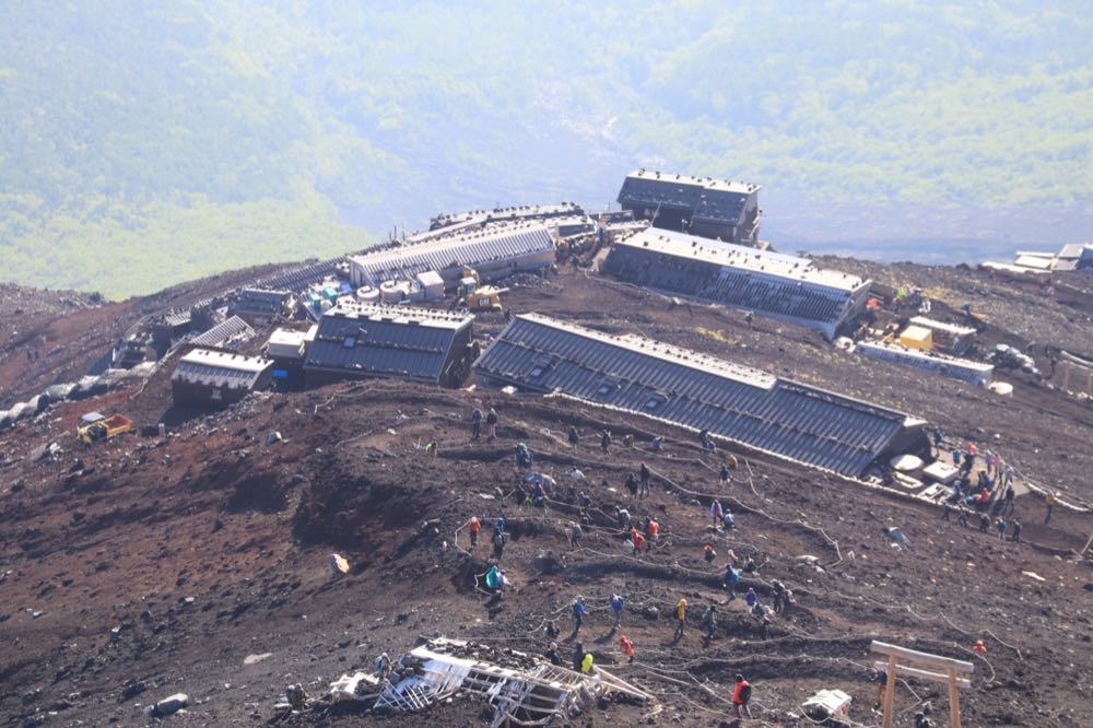 富士山の登山道、山小屋が並ぶ斜面と砂礫の急坂を歩く登山者たち
